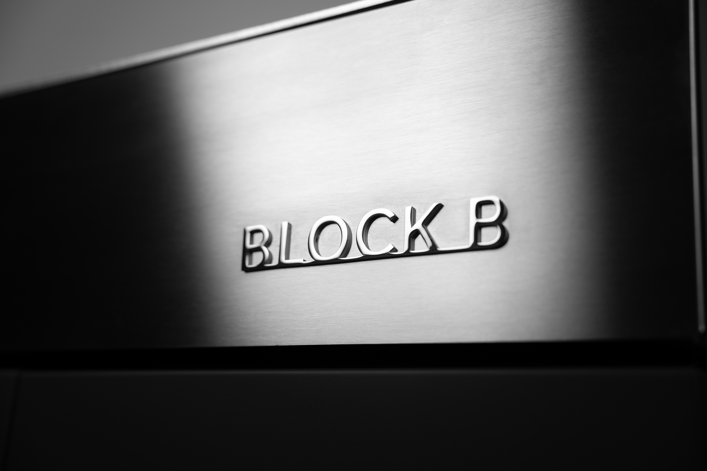 Nahaufnahme des reliefartigen, verchromten „BLOCK B“-Schriftzugs auf der gebürsteten Edelstahl-Front des Flammkraft Outdoor-Küchenmoduls.